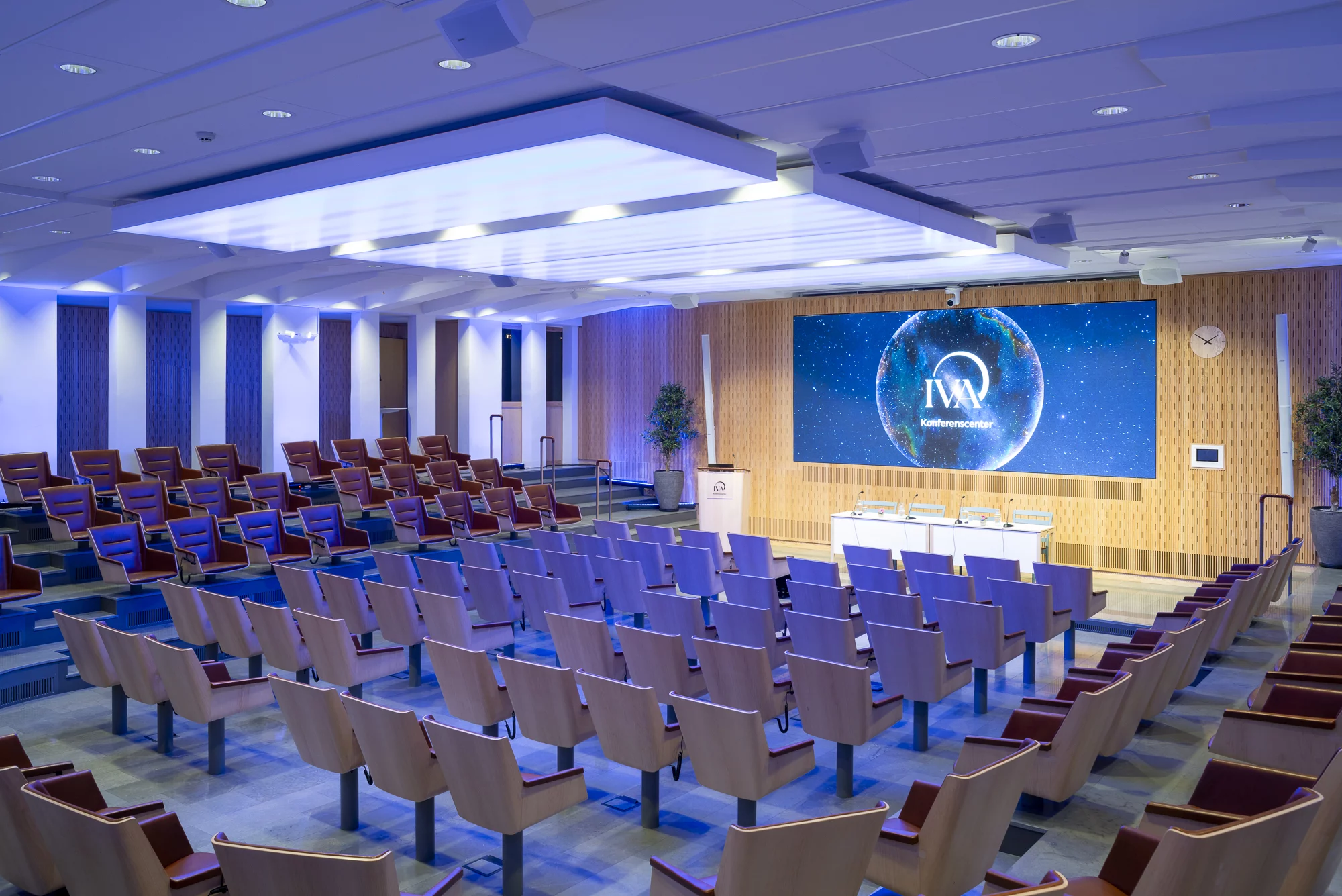 Wallenbergsalen på IVA Konferenscenter med gradängsittning, stor presentationskärm, panelbord och talarstol.